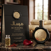 Grezna Mirsaal Valentine Eau de Parfum produktu ekspozīcija ar melnu 100 ml vaska plombas pudelīti un atbilstošu melnu dāvanu kastīti, kas noformēta ar rožu ziedlapiņām un zelta akcentiem uz klasiska galda klājuma.